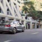 Silver 2016 Chevy Malibu Hybrid driving through a city.