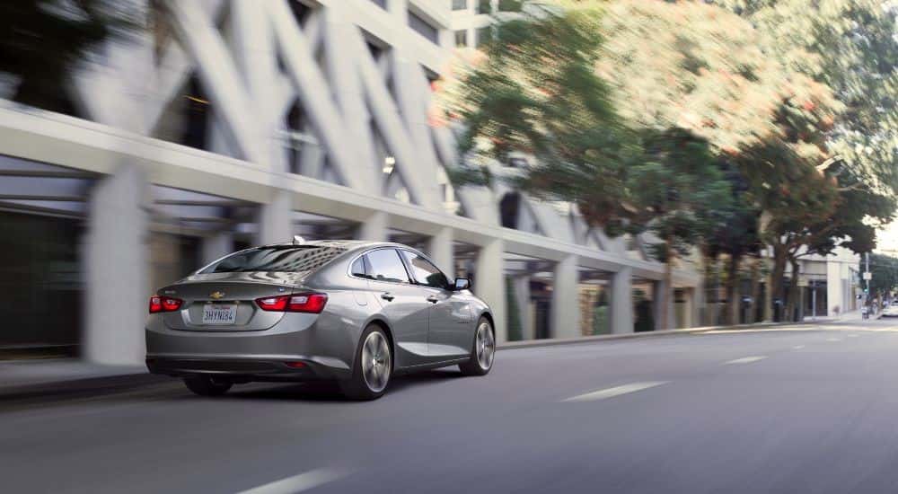 Silver 2016 Chevy Malibu Hybrid driving through a city.