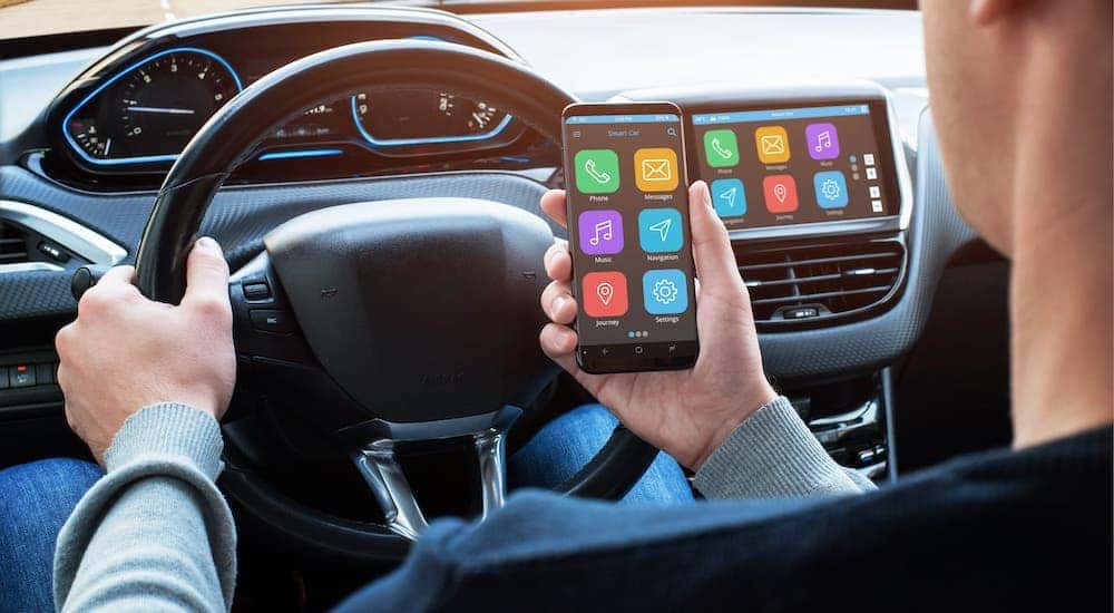 A man is testing his phone's compatibility with a car during a test drive.