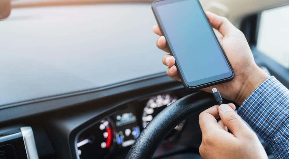 A person is shown plugging in a phone while sitting in a car after leaving a quick oil change.