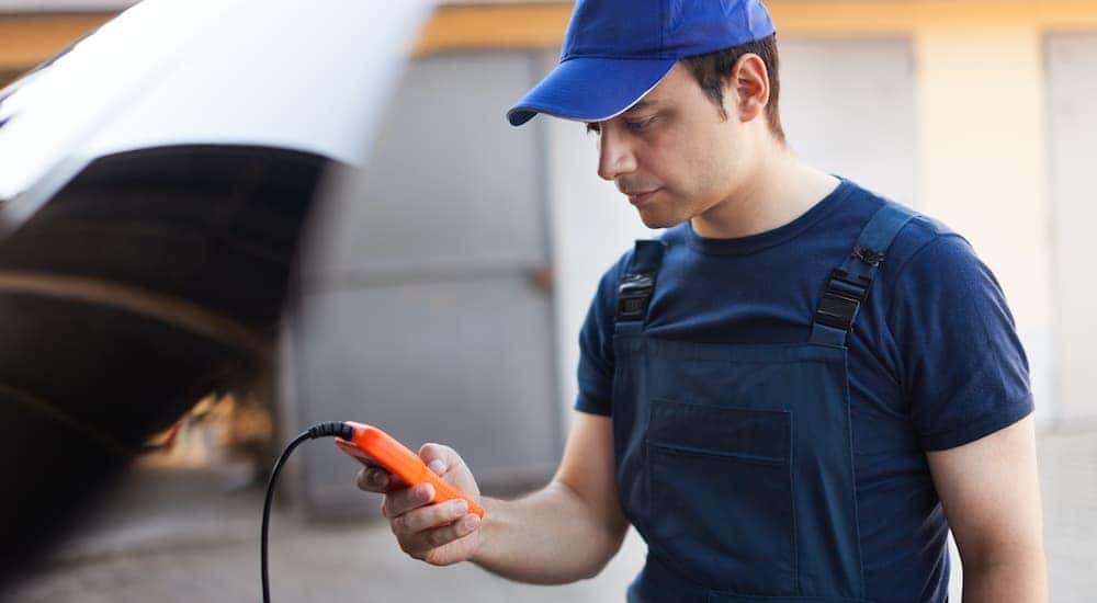 A mechanic is shown using a tester on a vehicle.