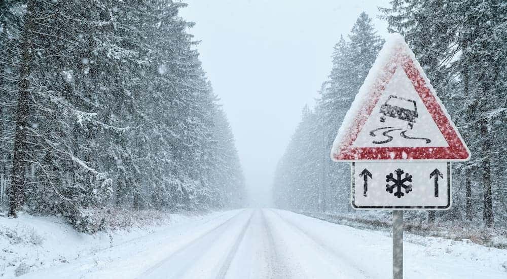 A close up shows a road sign on a snowy road.