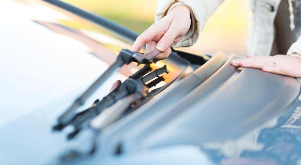 A hand is grabbing a wiper blade on a car.