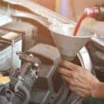 Hands are pouring transmission fluid into a funnel as part of an auto repair in Cincinnati.