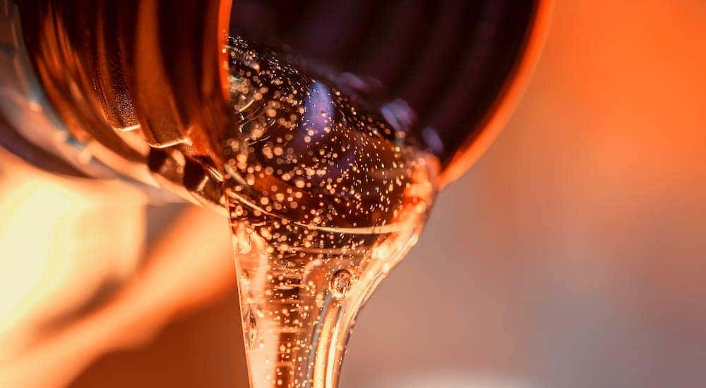 An extreme closeup shows amber oil being poured out of a container.