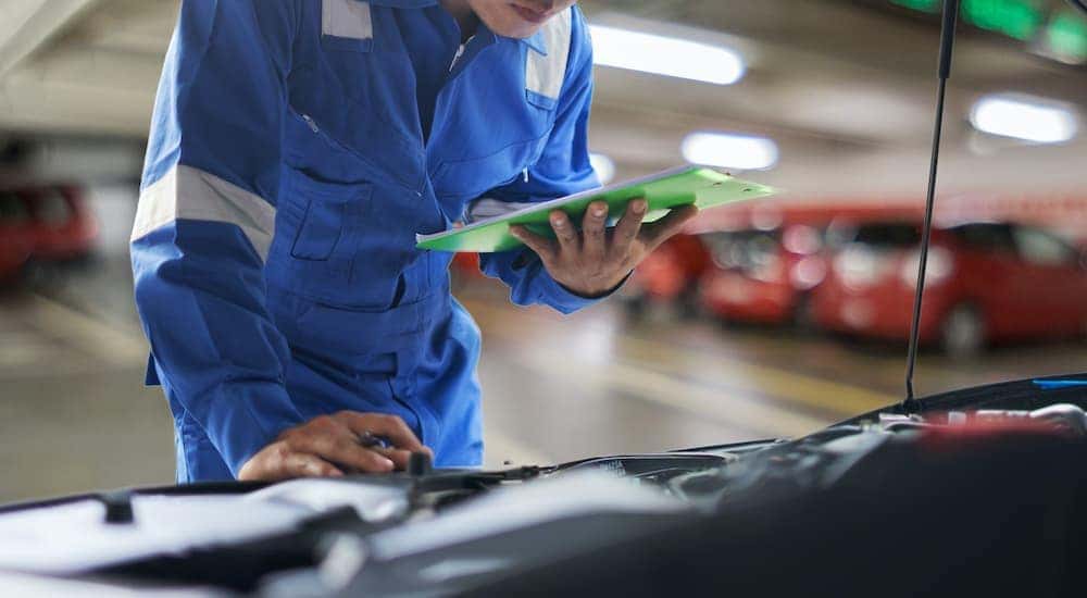 A mechanic is checking a cars engine.
