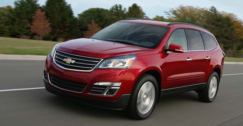 A red Chevy Traverse driving on a rustic highway
