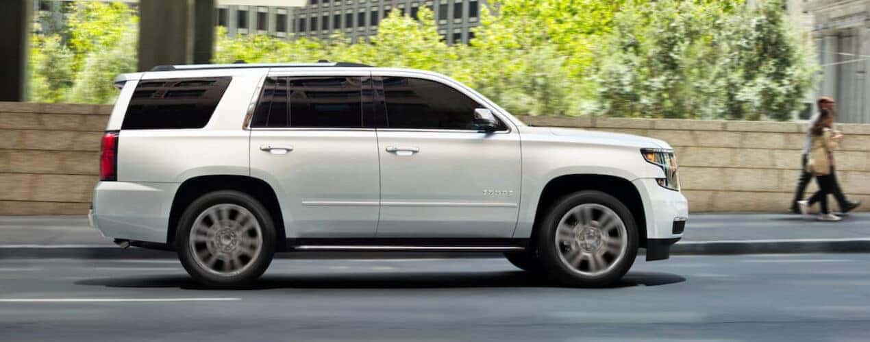 A white 2016 Chevy Tahoe driving on a city street.