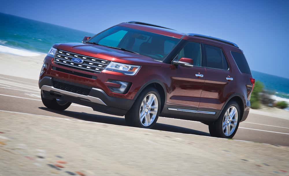 A red 2016 Ford Explorer is driving past the ocean.