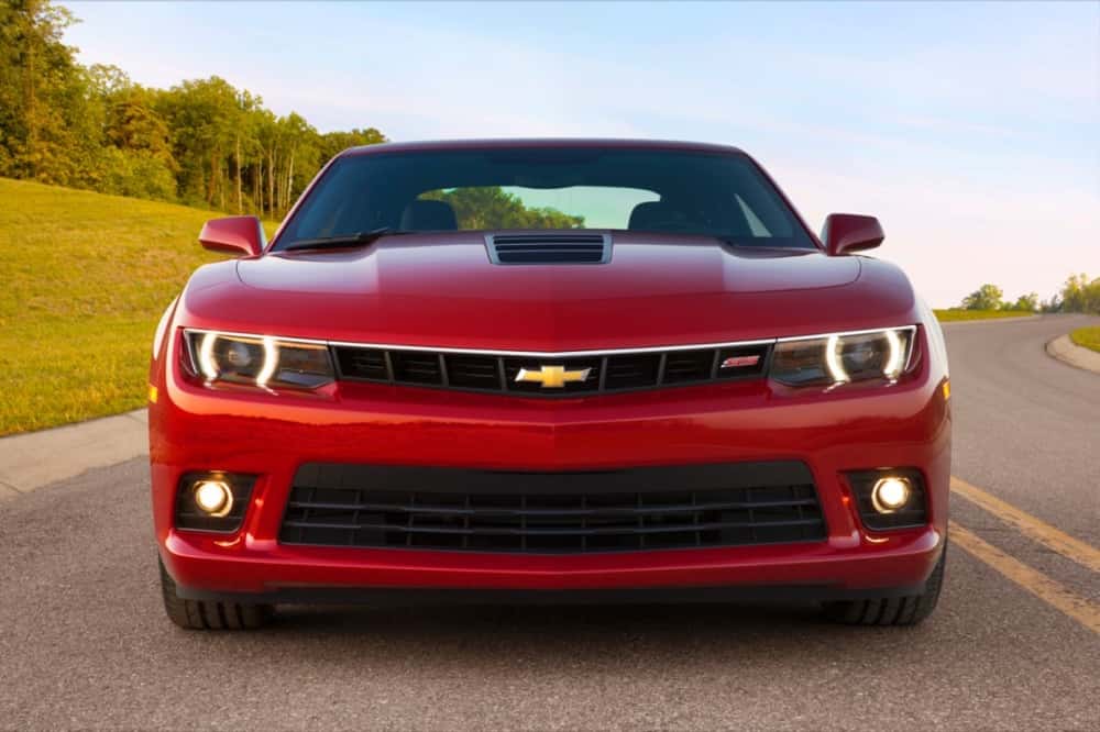 A red 2015 Chevy Camaro SS is shown from the front driving on a curvy road.