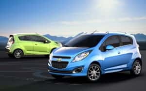 A blue and a green 2014 Chevy Spark are shown parked arfter visiting Indianapolis Chevy dealers.