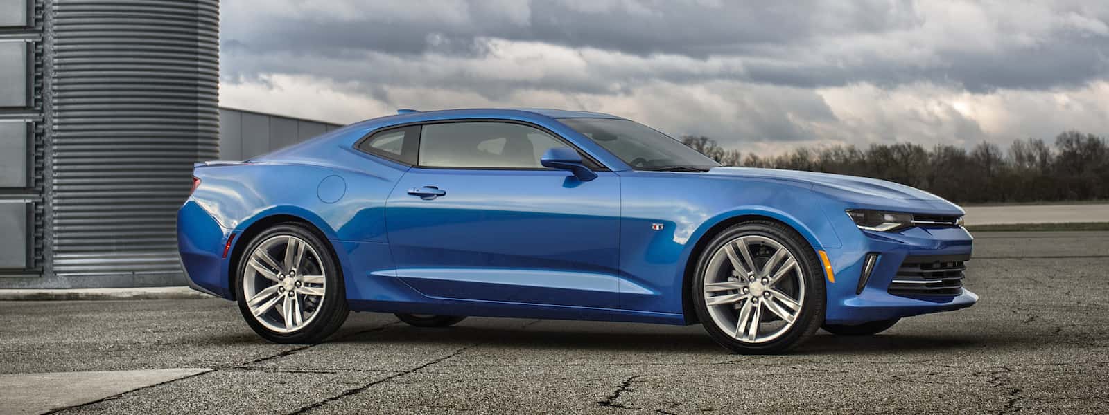 A blue 2016 Camaro is parked facing right in a parking lot.