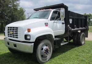 A large, white Chevy dump truck for sale is parked on a grassy field in Cincinnati.