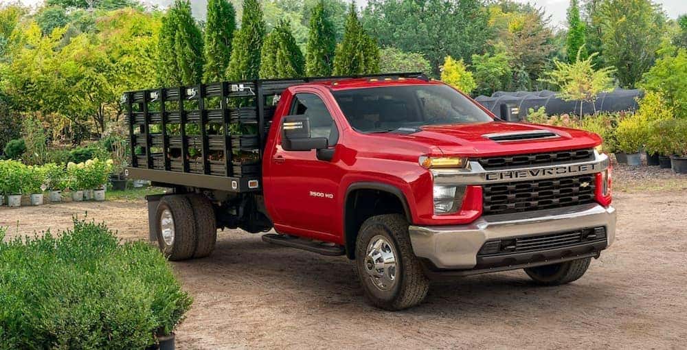 A red 2021 Chevy Silverado 3500 HD is shown parked in a garden nursery after looking for Chevy dump trucks.