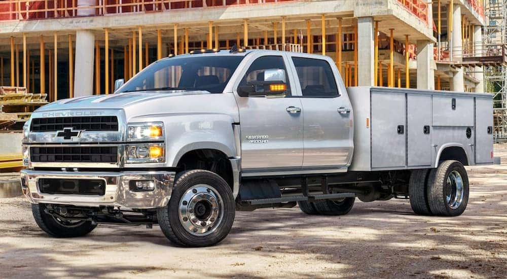 A silver 2021 Chevy Silverado 4500 HD is parked in front of a building project.
