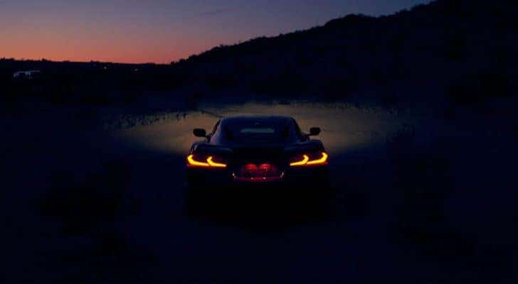 A red 2021 Chevy Corvette is shown front the rear with its lights illuminated at night.