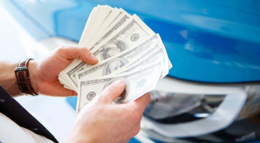 Car keys are being handed over in a car dealership in front of a red car.