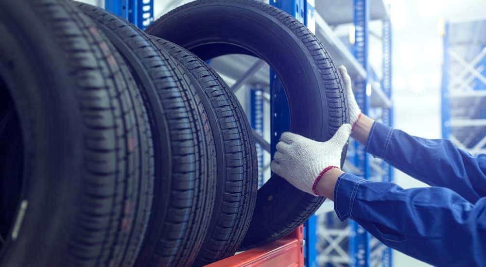 A gloved mechanic is pulling a tire down from the rack.