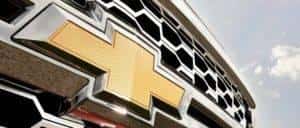 A closeup is shown of the gold Chevrolet bowtie emblem on a 2014 Silverado 1500.