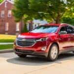 Red 2018 Chevy Equinox driving down a neighborhood road.
