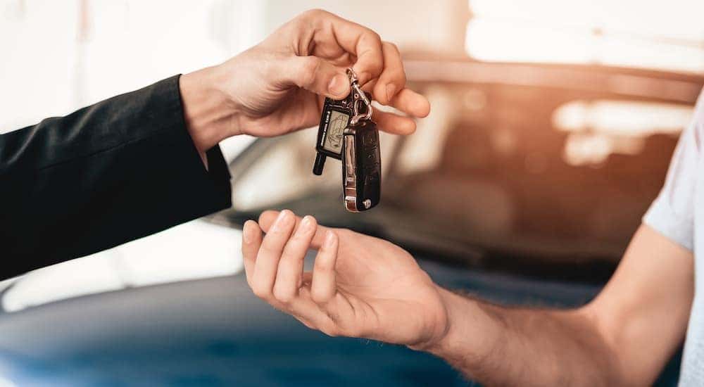 A set of car keys is shown being passed. 