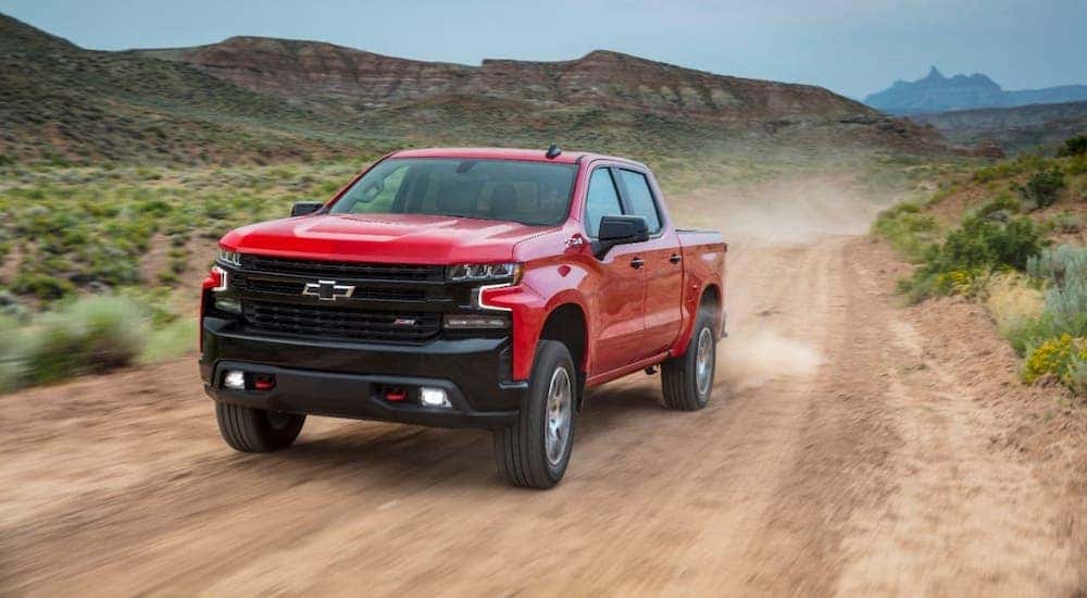 A great truck for sale for off roading, a red 2021 Chevy Silverado 1500 TrailBoss, is driving on a dirt trail.