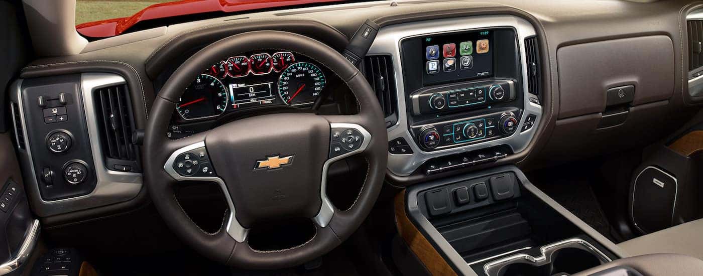 A view of the front interior of the 2018 Chevy Silverado with brown leather with black and chrome accents.