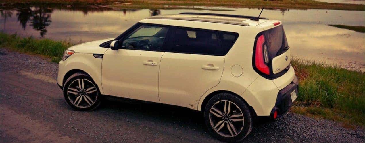 A white 2014 used Kia Soul is shown in front of a pond at dusk.