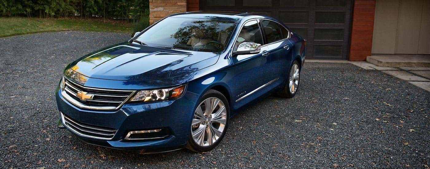 A blue 2018 Impala parked in front of a house garage