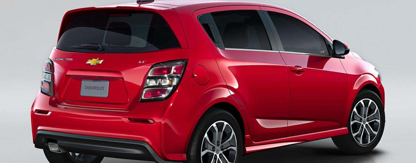 The rear passenger side of a red 2018 Chevy Sonic is parked.