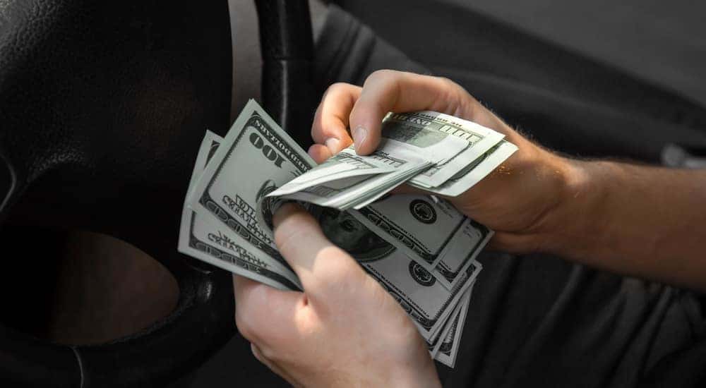 Someone is shown holding money while buying a vehicle at a buy here pay here in Indianapolis.