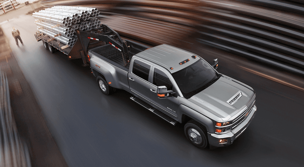 Silver 2018 Chevy Silverado 3500 hauling a trailer of pipes