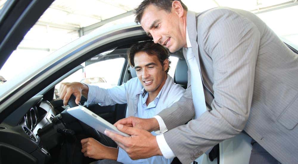 A car seller and car buyer looking at car information.