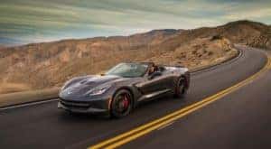 A dark grey 2014 Chevy Corvette is driving on a mountain road after checking out used cars, Dayton, Oh.