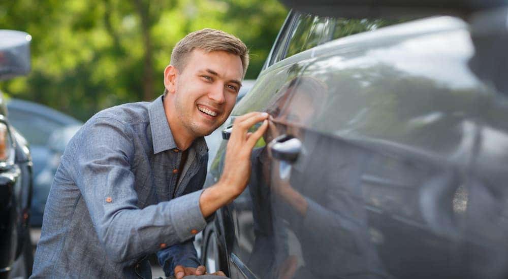A person is shown looking closely at a used car in Dayton, Ohio.