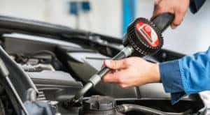 A technician add new oil to a car during an oil change at McCluskey Chevy