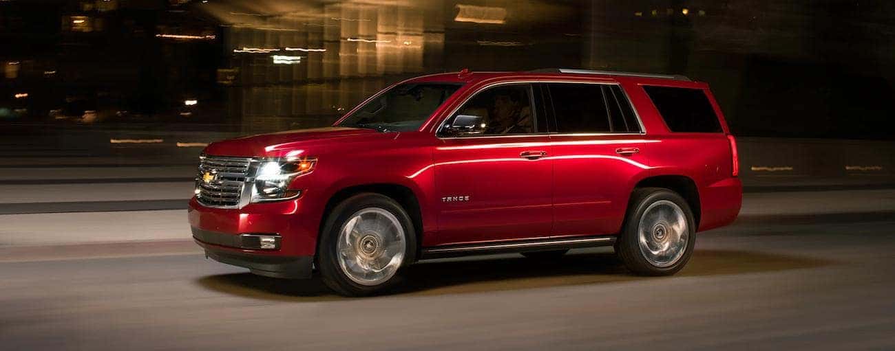 Red 2019 Chevy Tahoe driving on city street at night