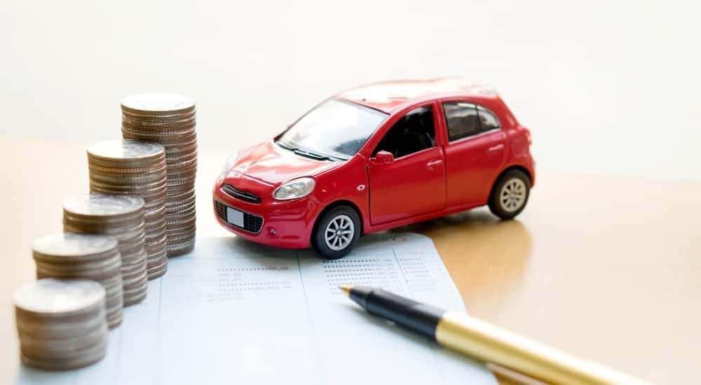 A red toy car next to stacks of coins is shown at a Buy Here Pay Here in Lexington.