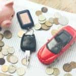 Papers, coins, piggy bank, car keys and toy car sitting on table