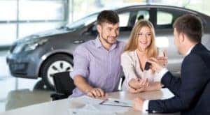 A happy couple is at a Cincinnati Chevy dealer discussing trade in value with a salesperson.