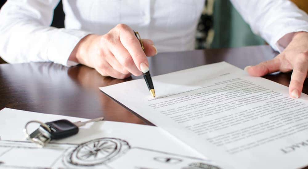 A person looking closely at paperwork with a car trade in value