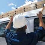A man loads a ladder on top of a 2019 Chevy Express cargo van