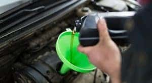 Pouring oil into a green funnel during an express oil change