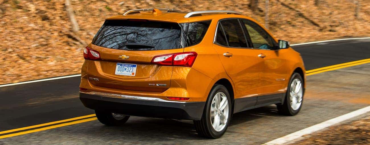 An orange 2019 Chevy Equinox driving up a woodland hill