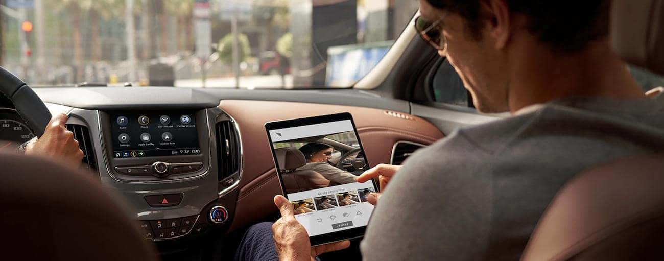 A look inside the 2019 Chevrolet Cruze while a man edits a photo on a tablet. Check out features when comparing the 2019 Chevy Cruze vs 2019 Nissan Sentra.