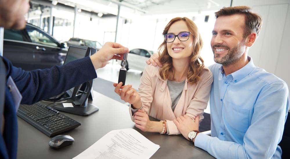 A couple is shown buying a car from McCluskey Chevy through a Buy Here Pay Here program.