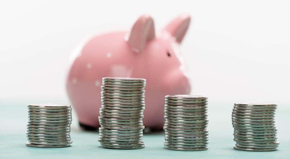 Stacks of coins in front of a piggy bank to budget for used cars