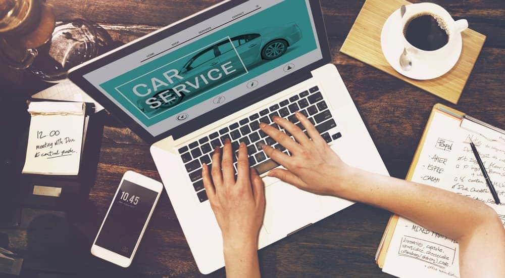 A woman at a cafe looking online for car service and cheap oil change shops in her area