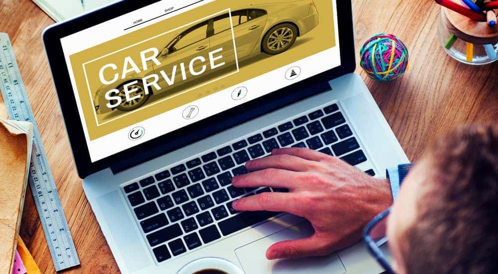 A man sits in his home office looking online for somewhere to get car service and a express oil change near him