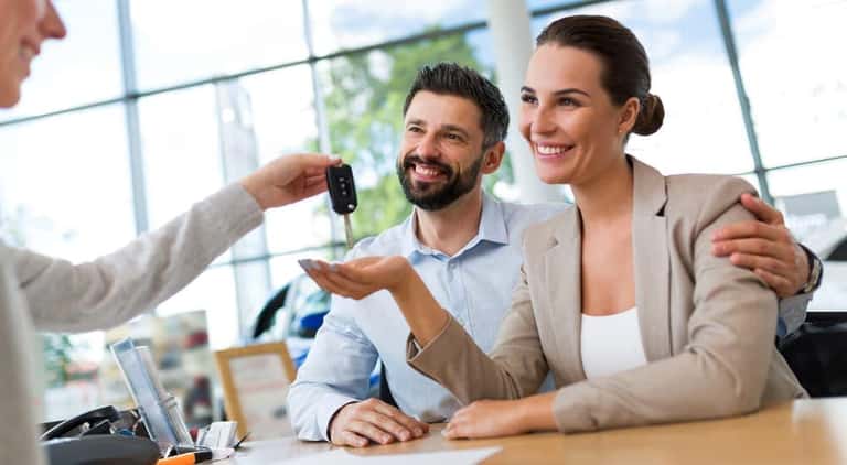 A couple is being handed their new car keys after purchasing at a Buy Here Pay Here dealer in Indianapolis.